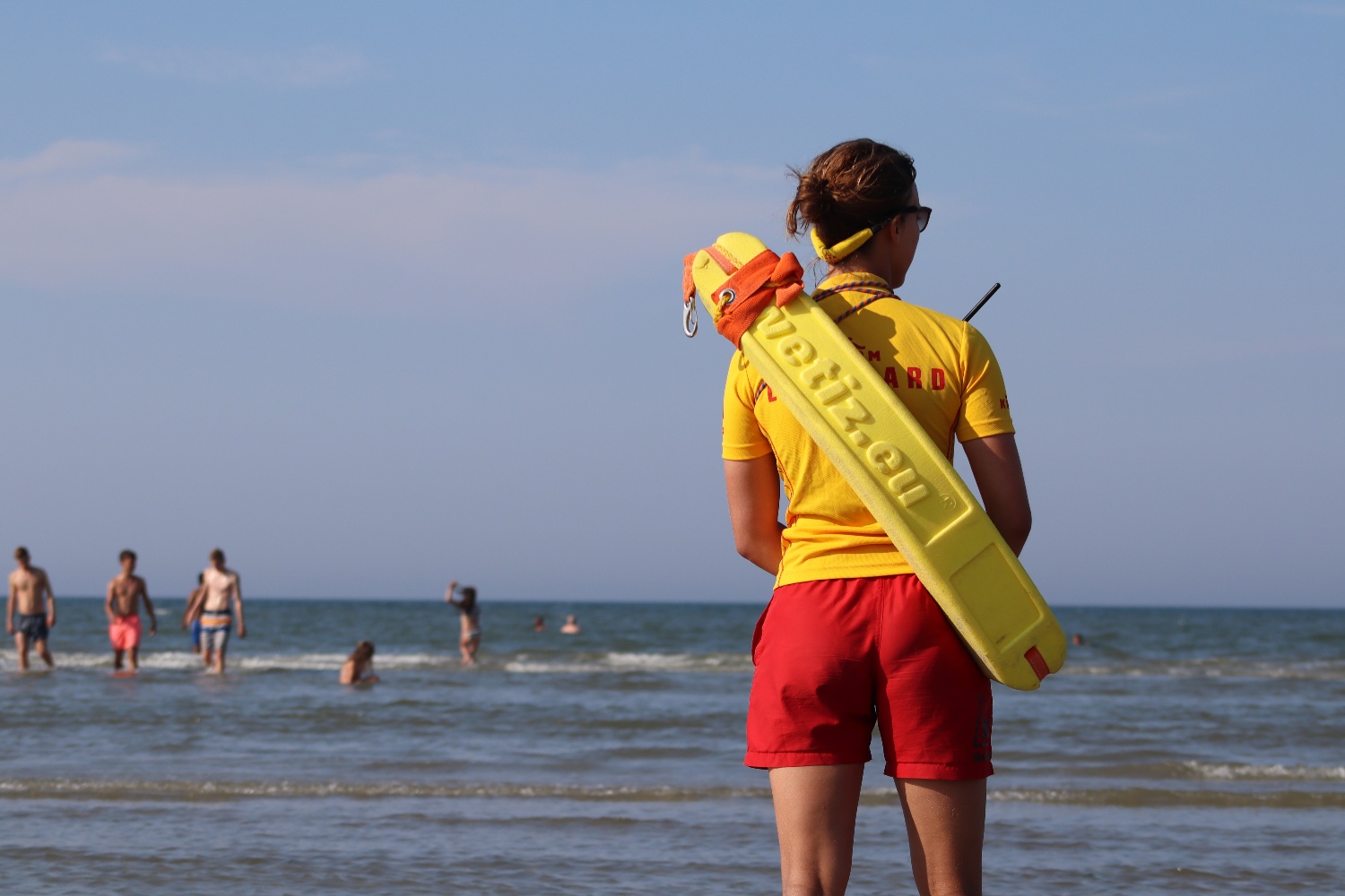 Lifeguard in yellow and red looking out to sea 